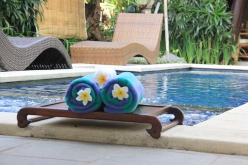 two towels with flowers on them sitting next to a swimming pool at Radiant Jepun Villa in Legian