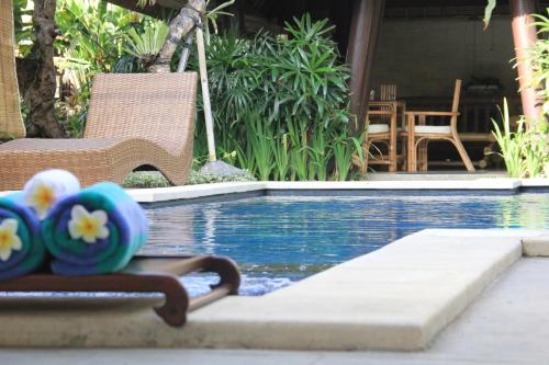 a pool with two beach balls and a chair next to it at Radiant Jepun Villa in Legian