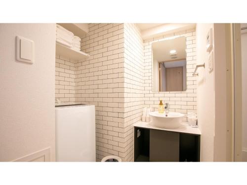 uma casa de banho branca com um lavatório e um espelho em ESLEAD HOTEL Namba Daikokucho - Vacation STAY 86023v em Osaka