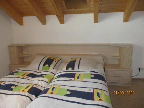 ein Bett mit zwei Kissen und einem Kopfteil aus Holz in der Unterkunft Ferienhaus Am Pfingstborn 