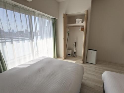 um quarto com uma cama branca e uma grande janela em ESLEAD HOTEL Namba Daikokucho - Vacation STAY 86023v em Osaka