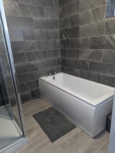 a white bath tub in a bathroom with tiled walls at Kings Head in Chepstow