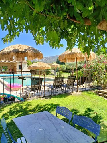 une table, des chaises, des parasols et une piscine dans l'établissement Le Faré Tchanqué gite 2 ch piscine parking wifi gratuit, à Cavaillon
