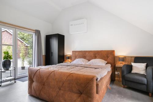 1 dormitorio con 1 cama grande y 1 silla en Luxurious nature stay in Friesland with jacuzzi, en Veenklooster