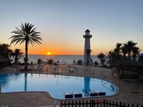 a swimming pool with a lighthouse in front of the ocean at INFINITY VIEW in Playa del Aguila