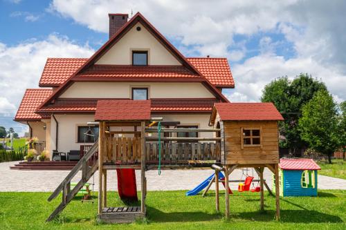 a house with a playground in front of a house at Noclegi Na Brzegu in Szaflary