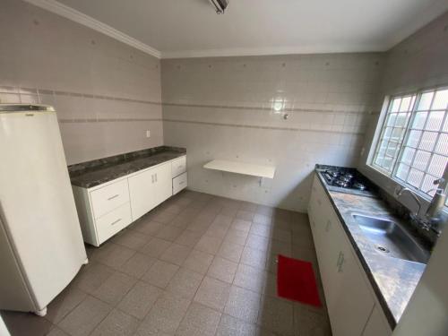 an empty kitchen with a sink and a refrigerator at Casa Comendador in Uberlândia