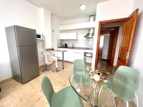 a kitchen with a glass table and green chairs at Little Home in Puerto del Rosario