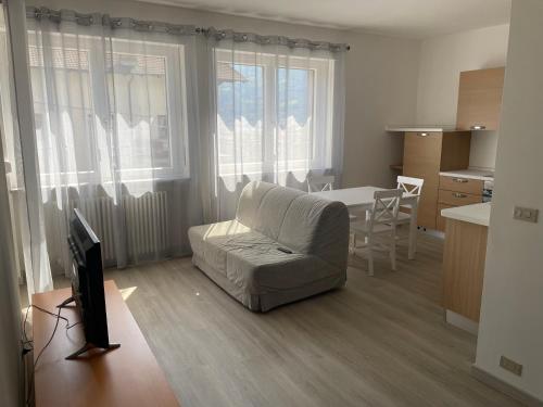 een woonkamer met een bank en een tafel en een keuken bij La Fiorita Aosta in Aosta
