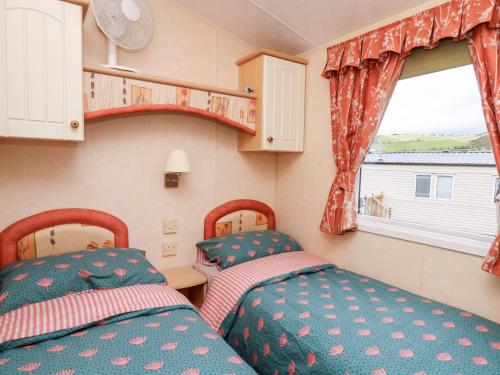 - 2 lits dans une petite chambre avec fenêtre dans l'établissement Bryn Vista, à Aberystwyth