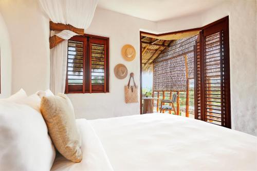 a bedroom with a white bed and a balcony at La Villa Luz (sólo adultos) in Zihuatanejo