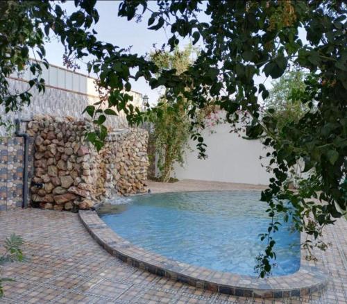 a swimming pool next to a stone wall at Juman B&B in Seeb