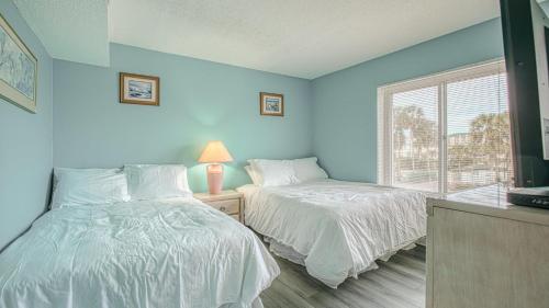 2 camas en una habitación con paredes azules y ventana en Destin on the Gulf 201 - Beach Front Property, en Destin