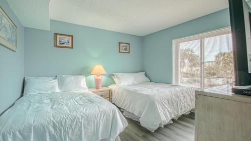 two beds in a room with blue walls and a window at Destin on the Gulf 201 - Beach Front Property in Destin