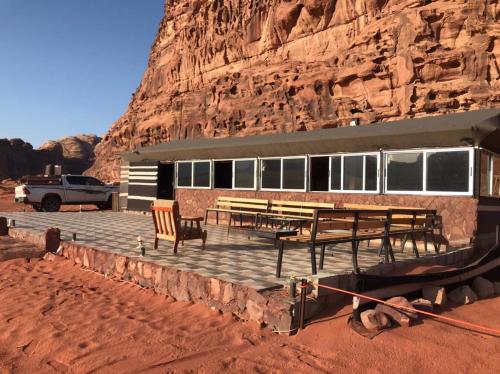un bâtiment avec des tables et des chaises en face d'une montagne dans l'établissement Omar Ghazi Camp, à Wadi Rum