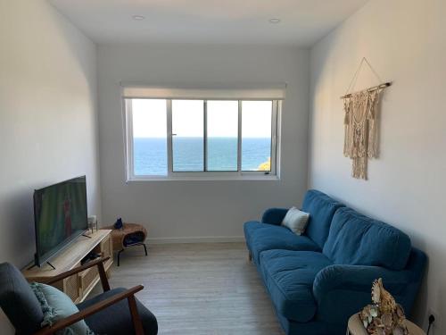 a living room with a blue couch and a window at Casa do Porto, relax with this stunning sea view in Porto Formoso