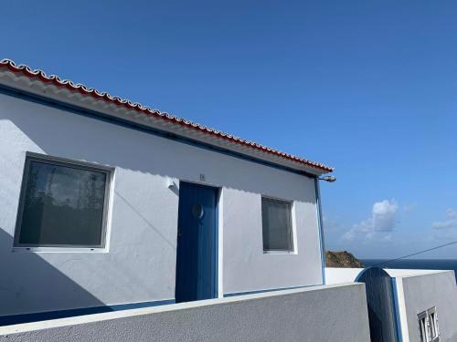 a white house with a blue door and a window at Casa do Porto, relax with this stunning sea view in Porto Formoso