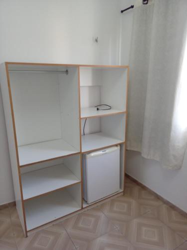 un armario con estanterías blancas en una habitación en O Farol Aluguel de Quartos en Beberibe