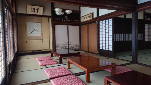Kominka Resort Nijuyondai - Vacation STAY 24402v في Nanyo: غرفة مع طاولة ووسائد وردية في غرفة مع نوافذ