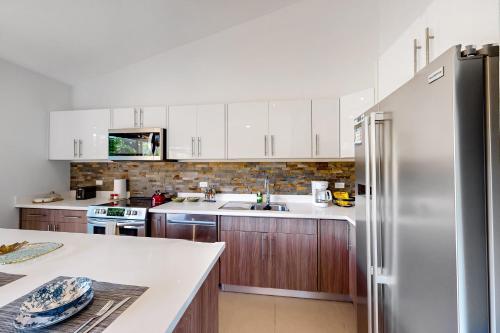 a kitchen with white cabinets and a stainless steel refrigerator at Ciudad del Mar 104 in Jacó