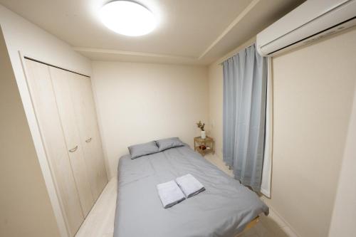 niewielka biała sypialnia z łóżkiem i oknem w obiekcie FL Rejidence Shinjuku 2 - Vacation STAY 15201 w Tokio