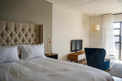 a bedroom with a large bed and a blue chair at Lush Studio Apartment with Back-Up Power. in Sandton