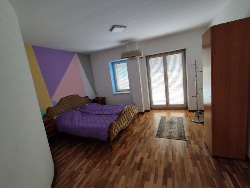 a bedroom with a purple bed and a wooden floor at Villa Ema rooms in Niš