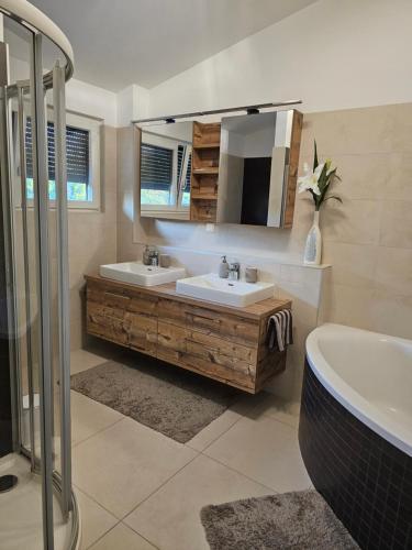 een badkamer met 2 wastafels, een bad en een spiegel bij Cosy & elegant Cityhouse with garden in Wenen