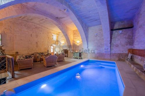 a large swimming pool in a room with a stone wall at VINTAGE FARMHOUSE in Qormi