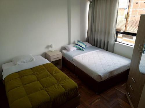 Duas camas num pequeno quarto com uma janela em DEPARTAMENTO AMOBLADO EN CUSCO em Cusco