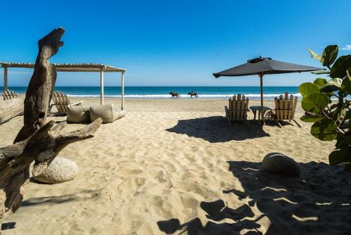 a beach with chairs and an umbrella and the ocean at KiChic in Máncora