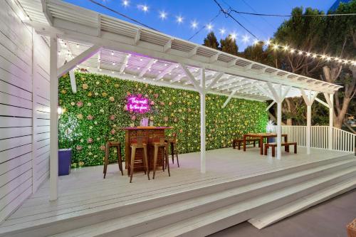 a patio with tables and a green wall with lights at Studio City Contemporary Villa with Pool Sleeps 10 in Los Angeles