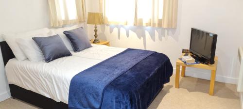 a bedroom with a bed with a blue blanket and a tv at Exquisite One Bedroom Apartment in the Heart of Sheffield City Centre in Sheffield