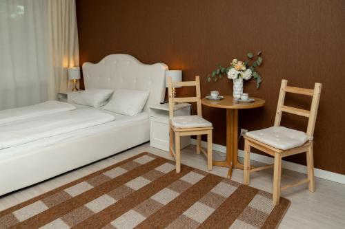 a bedroom with a bed and two chairs and a table at Hotel zum Hahn in Garbsen