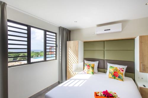 a bedroom with a bed and two windows at Coral Estate Ocean View Apartments in Willemstad