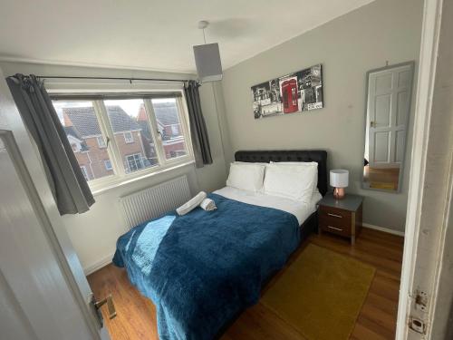 ein Schlafzimmer mit einem Bett mit einer blauen Decke und einem Fenster in der Unterkunft FilmonHomes in Oldbury