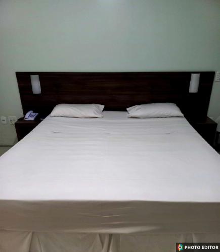a large white bed with a wooden headboard and two pillows at Hotel Adventure São Luís in São Luís
