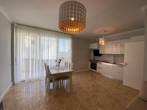 cocina y comedor con mesa y lámpara de araña en Adelina's Delux Apartament Durres en Durrës