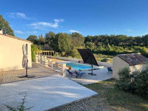 a swimming pool with an umbrella and a patio at Charmante maison avec piscine in Artignosc-sur-Verdon