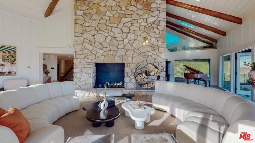 a living room with white couches and a stone fireplace at Beverly Estates in Los Angeles