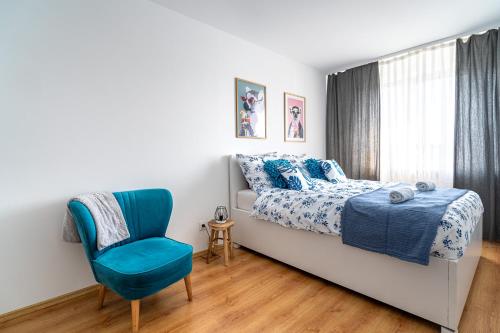 ein Schlafzimmer mit einem Bett und einem blauen Stuhl in der Unterkunft Apartament La Lemur in Nowy Sącz