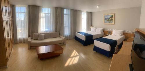 サンベルナルド・ド・カンポにあるPampas Palace Hotelのベッド2台とソファが備わるホテルルームです。
