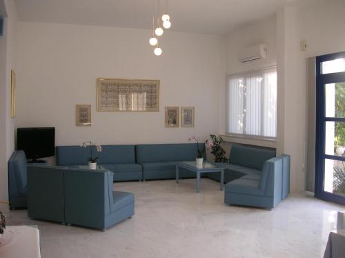 a living room with blue couches and a tv at Danae Hotel in Limenas