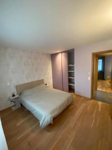 een slaapkamer met een wit bed en een houten vloer bij Maison ossature bois in Dole