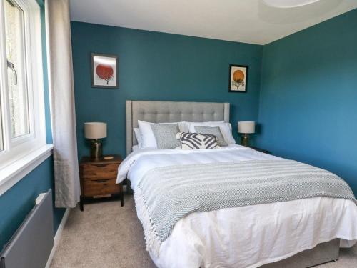 a bedroom with blue walls and a large bed at Beech Cottage in Aberfeldy