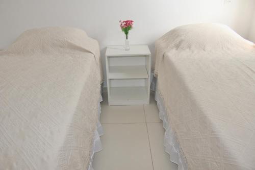 two beds next to a night stand with a vase of flowers at Clip d´Oro Hotel in Camaçari