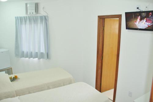 a room with a bed and a window and a tv at Clip d´Oro Hotel in Camaçari