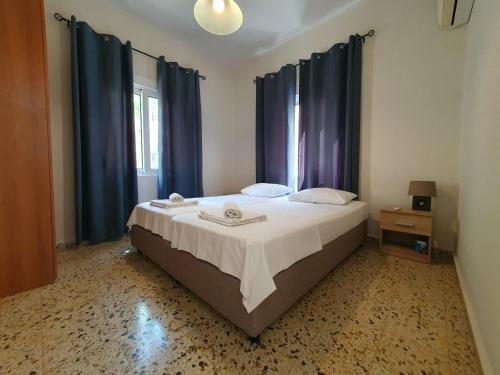 1 dormitorio con 1 cama grande y cortinas azules en Yiannis Sokaki House, en Rodas