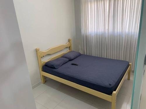 a small bedroom with a bed with a blue blanket at Quitinete Aconchegante Prq Pelinca in Campos dos Goytacazes