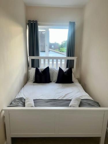 ein weißes Bett mit schwarzen Kissen in einem Zimmer in der Unterkunft 2 Bedroom Apartment with Balcony in Oxford